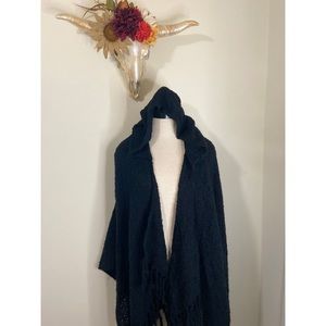 Black hooded cape with a fringed hem.
